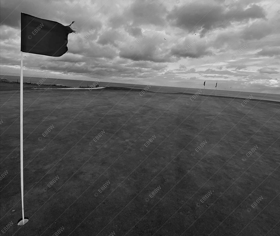Drapeau sur un green sous un ciel nuageux