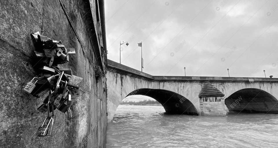 Grappe de cadenas contre un mur de pierre, un pont au loin