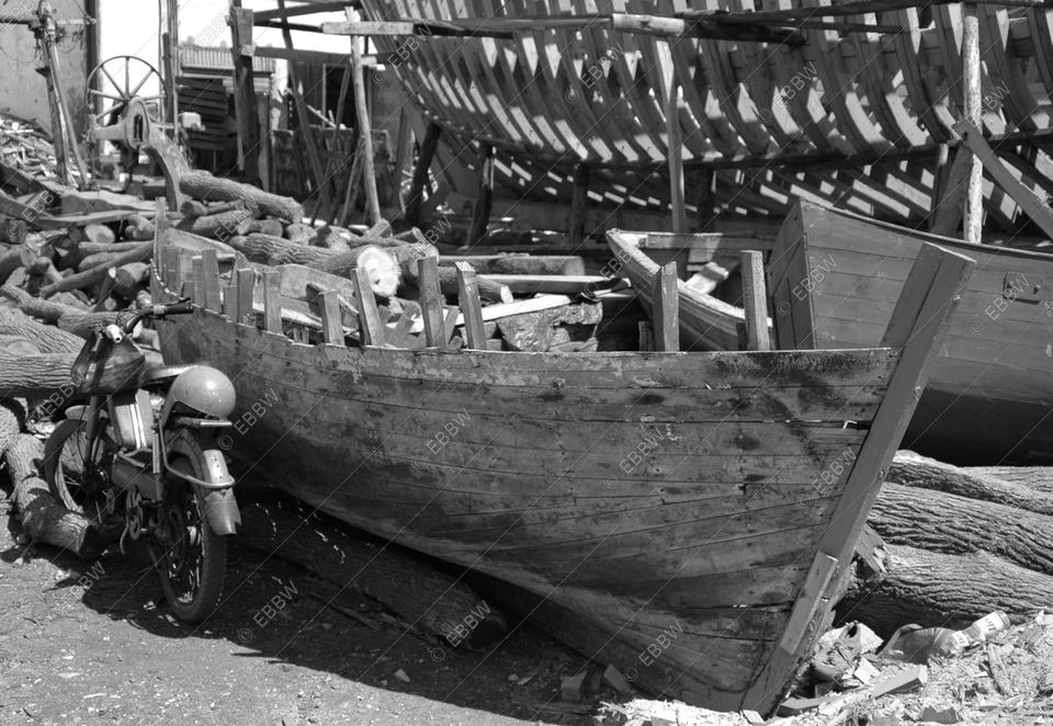 Moto garée près d’une barque en bois dans un chantier