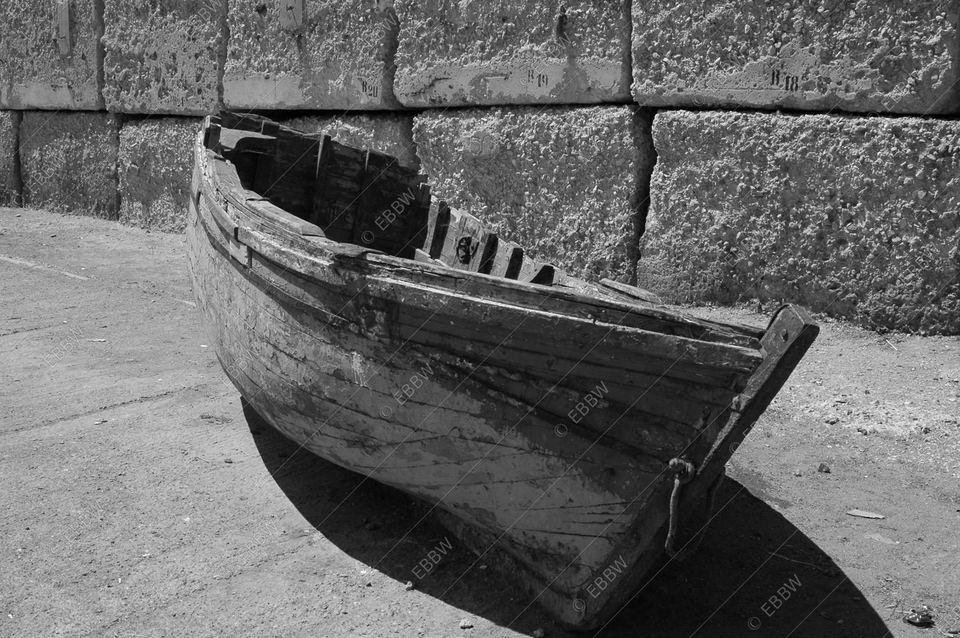 Vieille barque en bois échouée au pied d’un mur