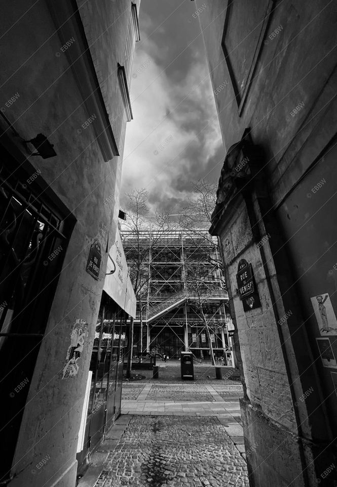 Ruelle sombre ouvrant sur une façade de verre